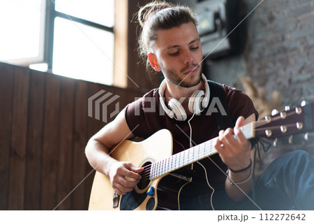 Handsome young man playing acoustic guitar sitting 112272642