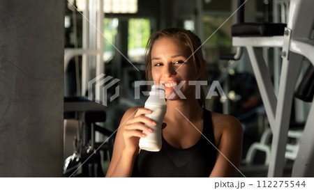 Healthy lifestyle woman drink milk at fitness gym. Young people girl workout exercise Healthy lifestyle woman drink milk at fitness gym. Young people girl workout exercise 112275544