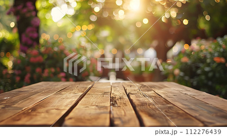 AI-generated content. A wooden table sits peacefully in a garden with vibrant flowers in the background, bathed in sunlight. The natural landscape features lush grass and a tree trunk, creating a 112276439