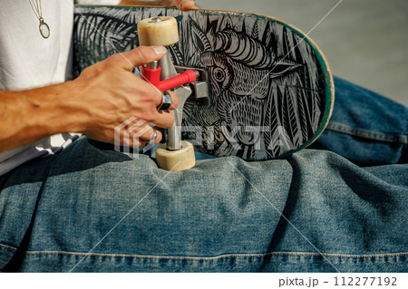 View of a man repairing his skateboard in the skate park. Extreme sport concept 112277192