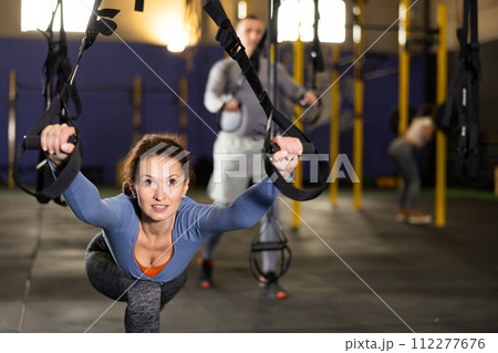 Female athlete with group working out on gymnastics rings at crossfit gym 112277676