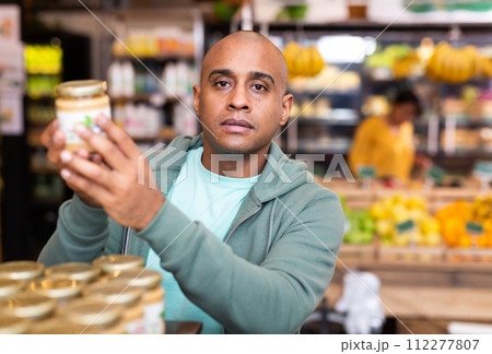 Positive man is choosing conserve in grocery supermarket 112277807