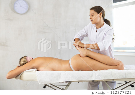 During massage, doctor works out legs shins kneads and stretches and increases mobility in joints 112277823