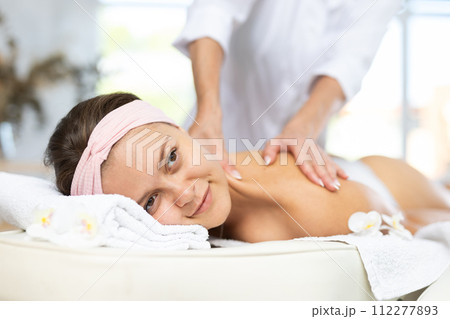 Young woman enjoying back and shoulders massage from professional masseuse Young woman enjoying back and shoulders massage from professional masseuse 112277893