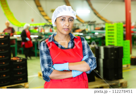Portrait of female worker in uniform with arms crossed standing in warehouse Portrait of female worker in uniform with arms crossed standing in warehouse 112278451