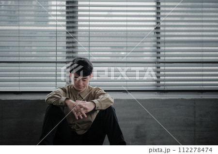 暗い部屋で落ち込んでいる若い男性 112278474