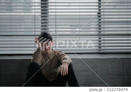 暗い部屋で落ち込んでいる若い男性 112278479