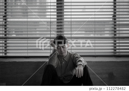 暗い部屋で落ち込んでいる若い男性 暗い部屋で落ち込んでいる若い男性 112278482