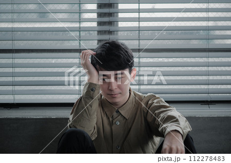 暗い部屋で落ち込んでいる若い男性 112278483
