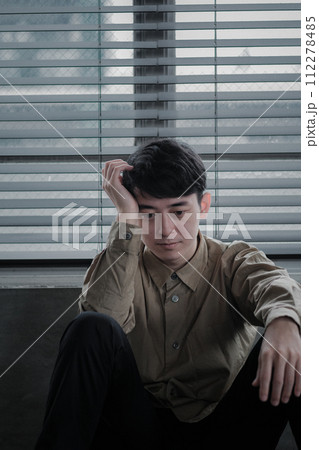 暗い部屋で落ち込んでいる若い男性 112278485