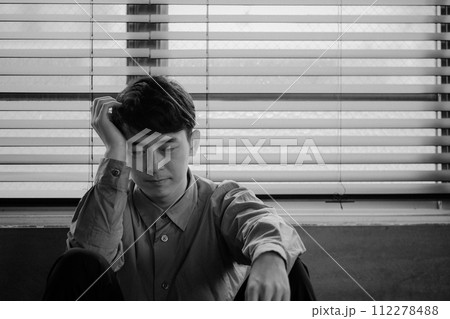 暗い部屋で落ち込んでいる若い男性 112278488