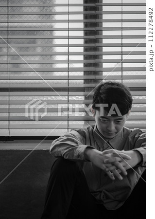暗い部屋で落ち込んでいる若い男性 112278492