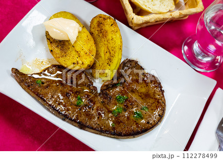 Tasty roast veal liver with baked potatoes served at plate, spanish dish Tasty roast veal liver with baked potatoes served at plate, spanish dish 112278499
