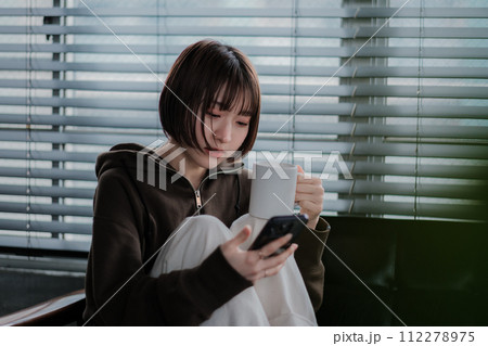 部屋着でソファーに座ってスマホを見る女性 部屋着でソファーに座ってスマホを見る女性 112278975