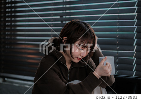 部屋着でソファーに座ってスマホを見る女性 112278983