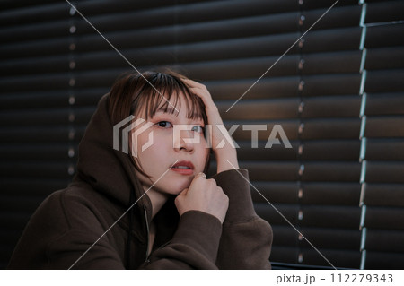 暗い部屋で落ち込んでいる女性 112279343