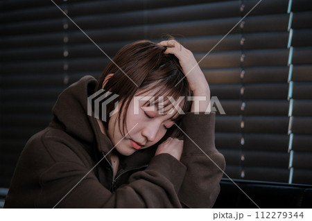 暗い部屋で落ち込んでいる女性 112279344