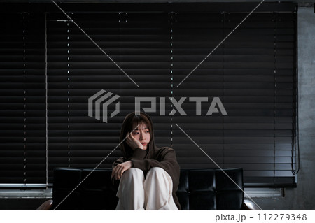 暗い部屋で落ち込んでいる女性 暗い部屋で落ち込んでいる女性 112279348