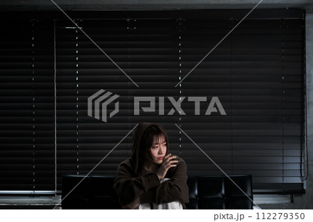 暗い部屋で落ち込んでいる女性 112279350