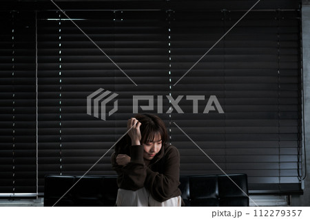 暗い部屋で落ち込んでいる女性 112279357