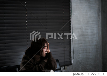 暗い部屋で落ち込んでいる女性 112279364