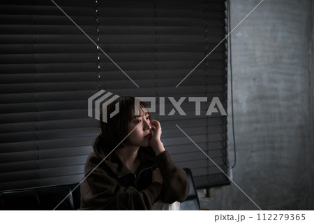 暗い部屋で落ち込んでいる女性 112279365
