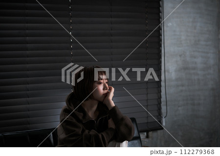 暗い部屋で落ち込んでいる女性 112279368