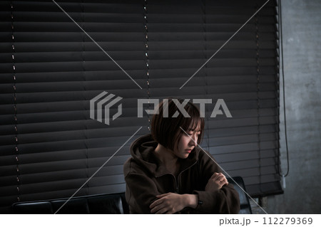暗い部屋で落ち込んでいる女性 暗い部屋で落ち込んでいる女性 112279369
