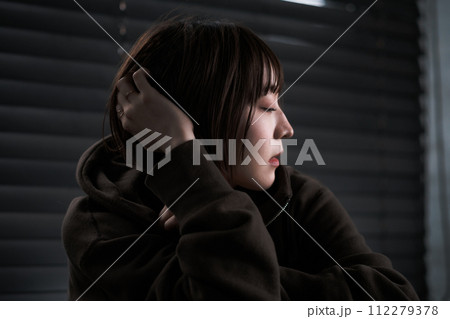 暗い部屋で落ち込んでいる女性 112279378