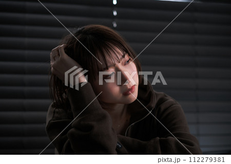 暗い部屋で落ち込んでいる女性 暗い部屋で落ち込んでいる女性 112279381