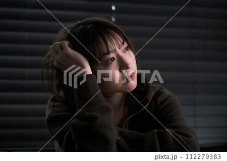 暗い部屋で落ち込んでいる女性 112279383