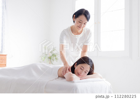 マッサージを受ける若い女性とエステティシャン マッサージを受ける若い女性とエステティシャン 112280225