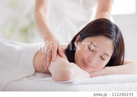マッサージを受ける若い女性とエステティシャン マッサージを受ける若い女性とエステティシャン 112280235