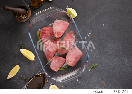 Pieces of Fresh tuna Fish fillet in glass cooking dish and soy sauce marinade in a gravy boat 112281241