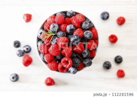 Ripe sweet blueberries and raspberries in a bowl. Closeup. 112281596