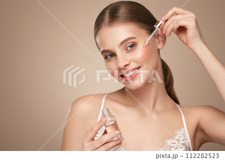 Young beautiful woman applying face serum 112282523