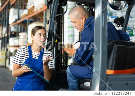 Young woman and elderly man working on loader check documents 112283247