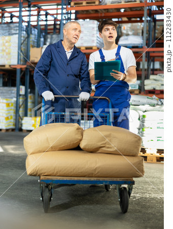 Elderly man and young guy check documents in warehouse 112283430