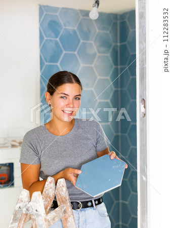 Woman checks quality of ceramic tiles in a bathroom being renovated Woman checks quality of ceramic tiles in a bathroom being renovated 112283532