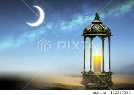 Ornamental Arabic lantern with burning candle glowing Ornamental Arabic lantern with burning candle glowing 112283580