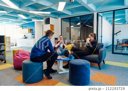 Multiethnic startup business team on meeting in a modern bright open space coworking office. Brainstorming, working on laptop. Group of coworkers walking around in motion blur 112283729