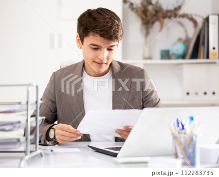 Male bookkeeper doing paperwork in workplace in office - checks accounting documents 112283735