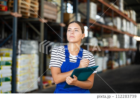 In warehouse of store, girl checks quantity of goods and receipt documents for products In warehouse of store, girl checks quantity of goods and receipt documents for products 112283739