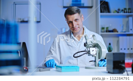 Confident man laboratory worker smiling on camera, scientist conducting research Confident man laboratory worker smiling on camera, scientist conducting research 112284791