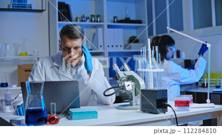 Nervous laboratory worker noticing mistake in test results on laptop, negligence Nervous laboratory worker noticing mistake in test results on laptop, negligence 112284810