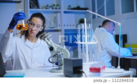 Cosmetic lab assistant mixing liquid substances, observing reaction, experiment Cosmetic lab assistant mixing liquid substances, observing reaction, experiment 112284819