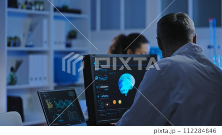 Male laboratory worker examining brain mri on display, conducting diagnostics Male laboratory worker examining brain mri on display, conducting diagnostics 112284846