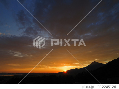 夏の磐梯山の夕景。日没直前、オレンジ色に輝く太陽と雲にシルエットの山が印象的で綺麗だ。 112285126