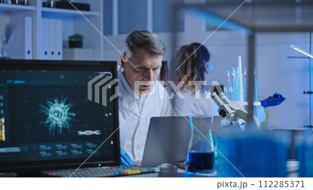 Biological laboratory scientist studying experiment results on laptop, research 112285371