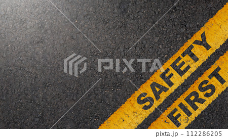 Safety first with yellow sign on asphalt road, warning concept of industrial attention for employee awareness. 112286205